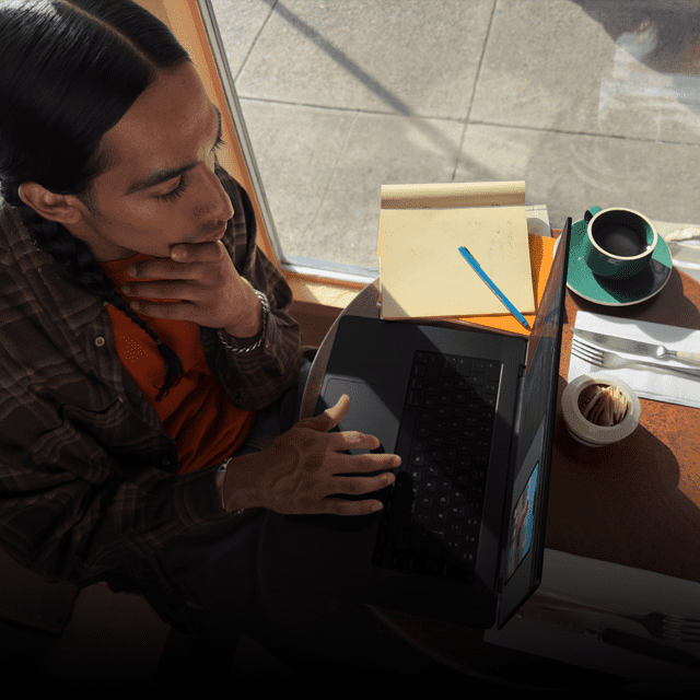 Egy férfi dolgozik egy kihúzott MacBook Pro-n egy kávézóban.